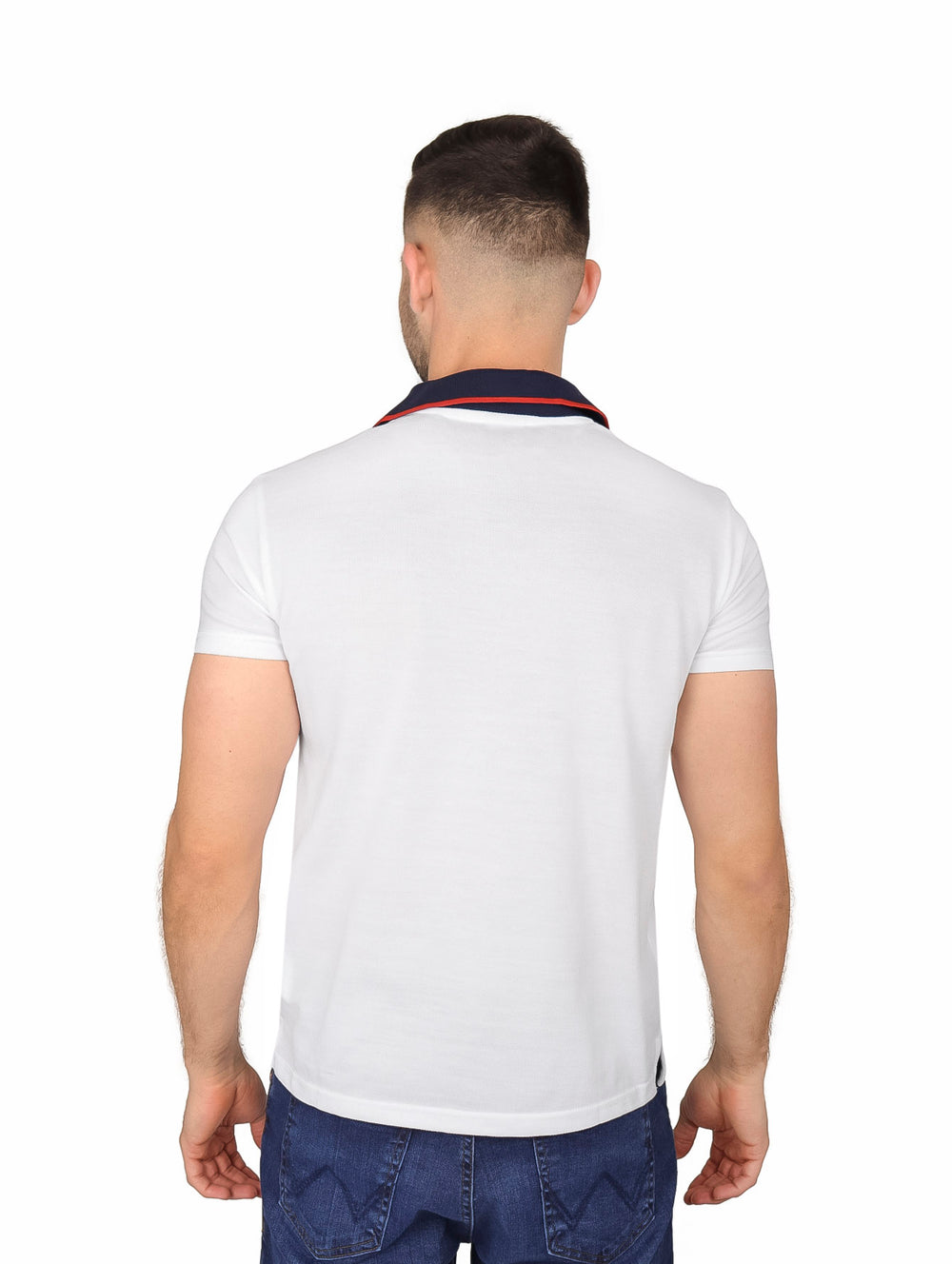 Hombre vistiendo playera polo blanca de manga corta con cuello en contraste azul marino y detalle rojo.