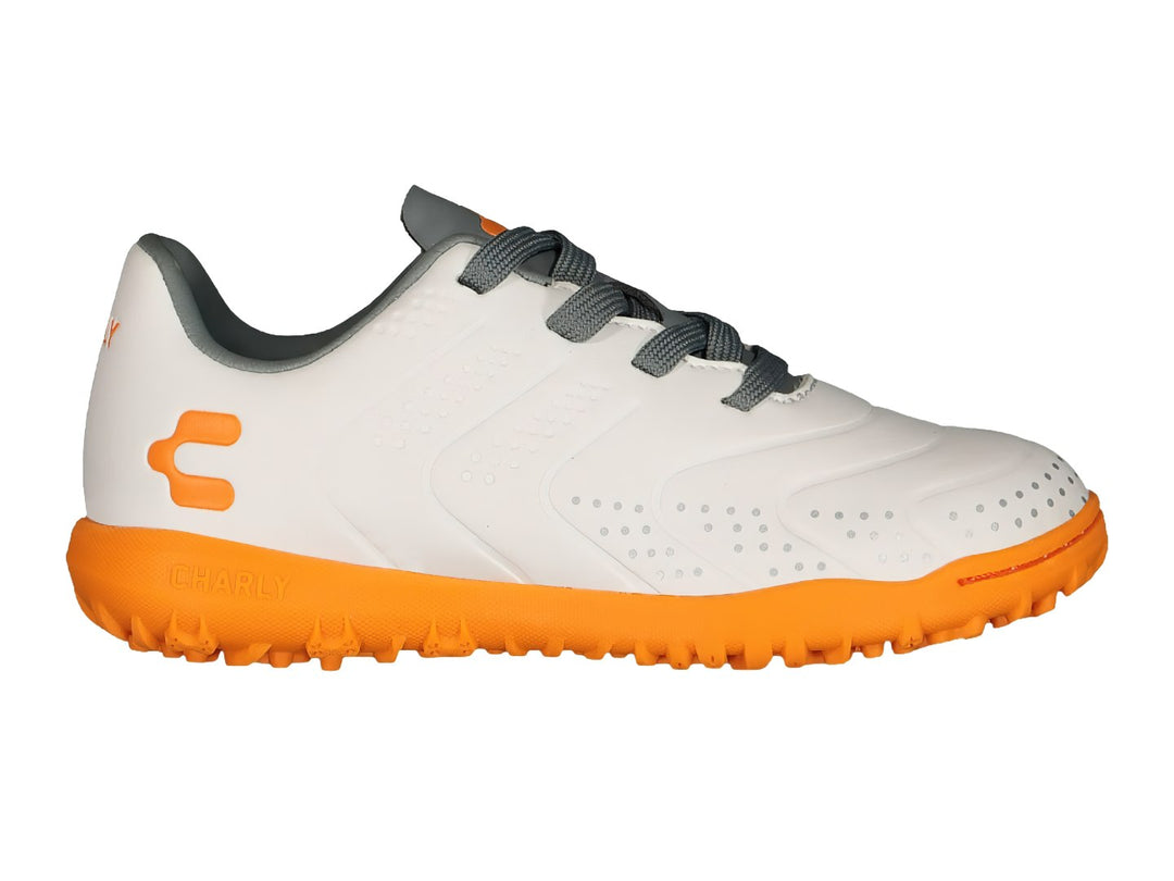 Tenis de fútbol Charly color blanco con suela naranja y detalles en gris.