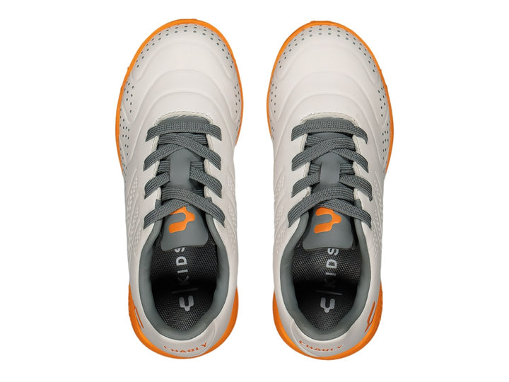 Tenis de fútbol Charly color blanco con suela naranja y detalles en gris.