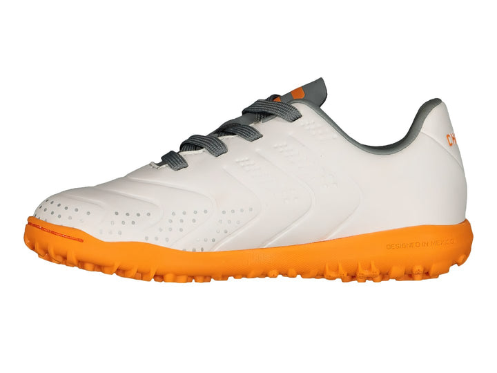 Tenis de fútbol Charly color blanco con suela naranja y detalles en gris.