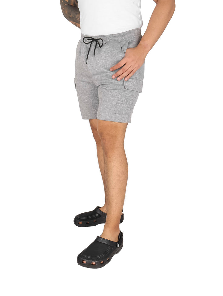 Hombre vistiendo pantalones cortos de color gris con cordón ajustable y bolsillos laterales.