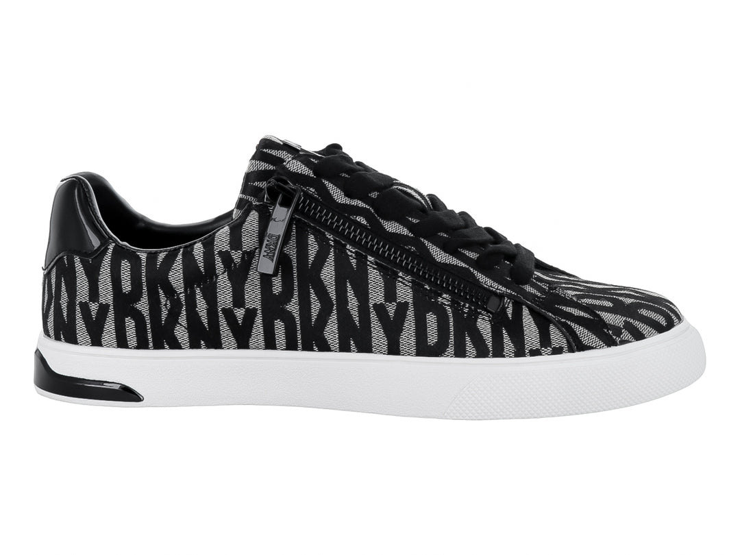 Tenis DKNY con estampado en negro y beige, suela blanca y cierre lateral.