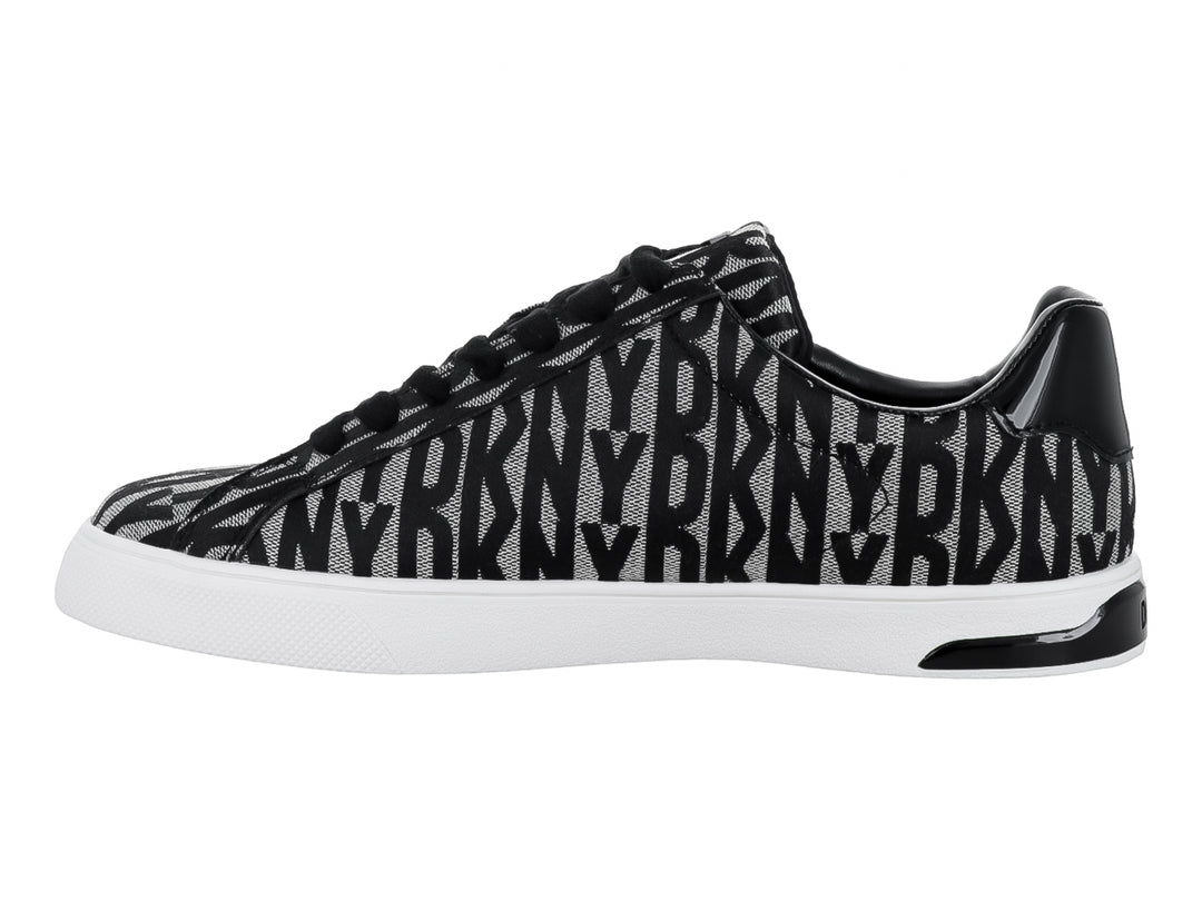 Tenis DKNY con estampado en negro y beige, suela blanca y cierre lateral.