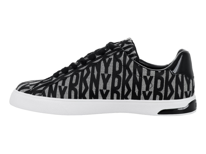 Tenis DKNY con estampado en negro y beige, suela blanca y cierre lateral.