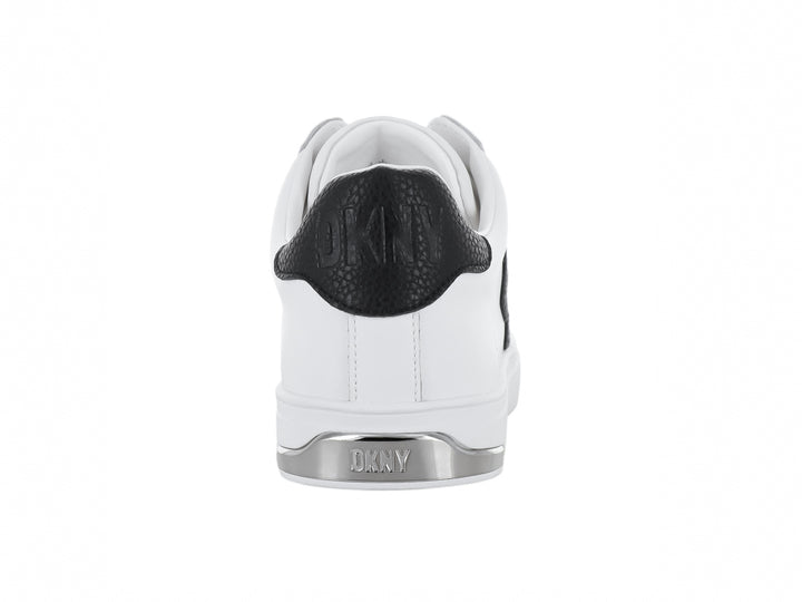 Tenis blancos DKNY con logotipo negro en el lateral y suela blanca.