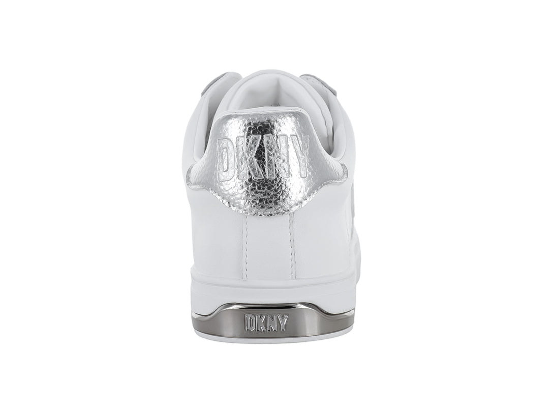 Tenis DKNY color blanco con letras decorativas en color plateado y suela blanca.