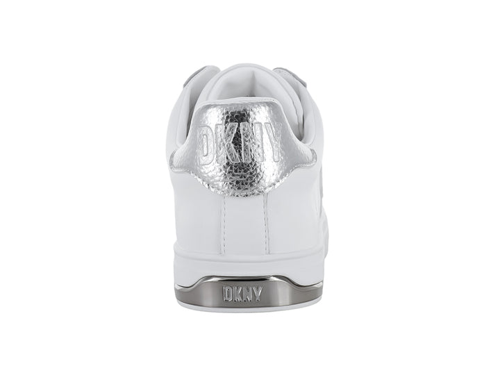 Tenis DKNY color blanco con letras decorativas en color plateado y suela blanca.