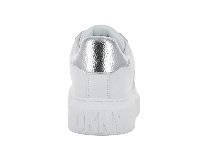 Tenis blancos DKNY con suela de plataforma y logotipo plateado en el costado.