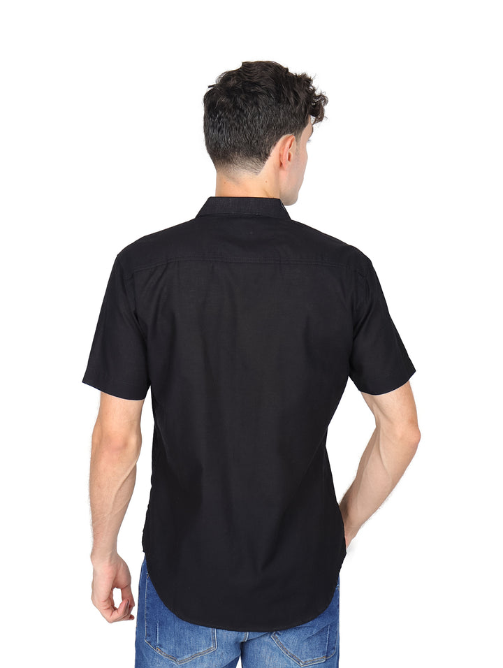 Hombre vistiendo una camisa negra de manga corta con botones y cuello.