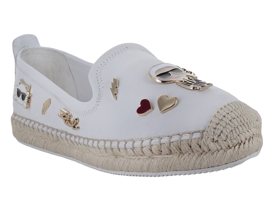 Zapato blanco tipo alpargata con suela de yute y detalles metálicos decorativos.