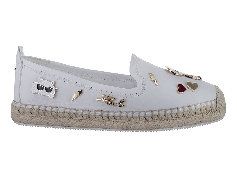 Zapato blanco tipo alpargata con suela de yute y detalles metálicos decorativos.