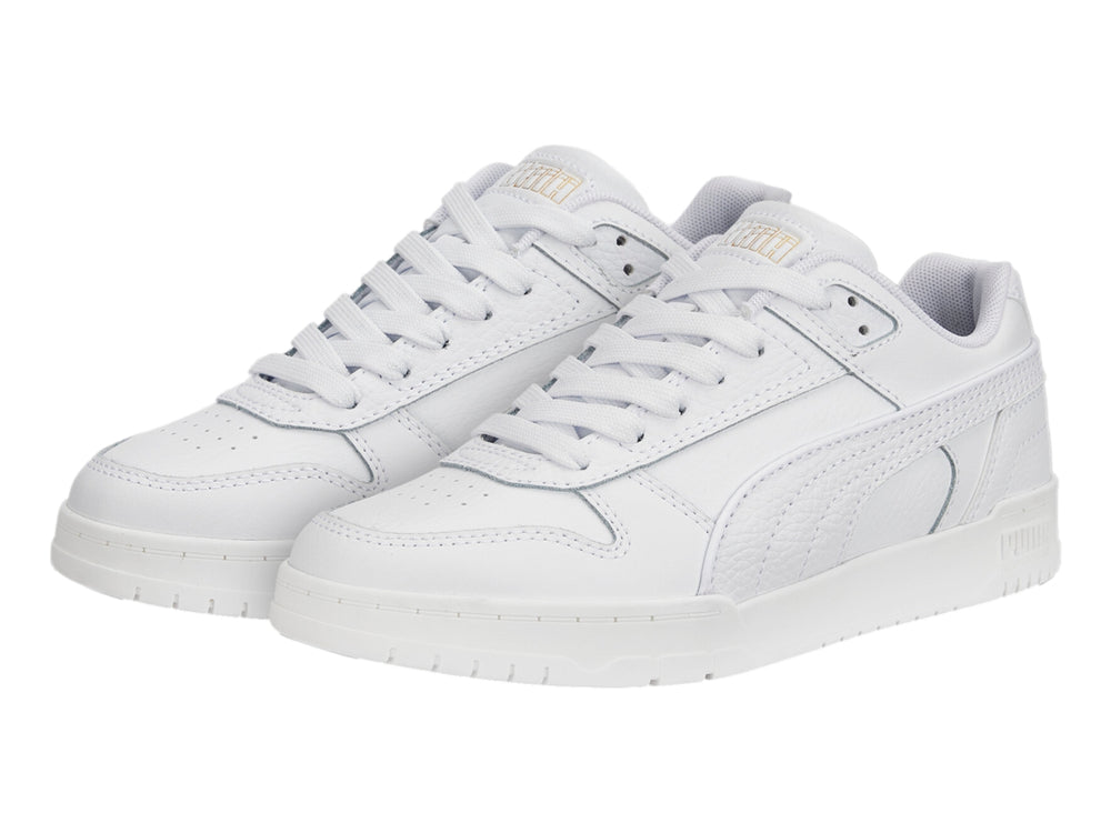 Tenis PUMA RBD Game Low JR en color blanco con detalles dorados, diseño deportivo de corte bajo para niños.