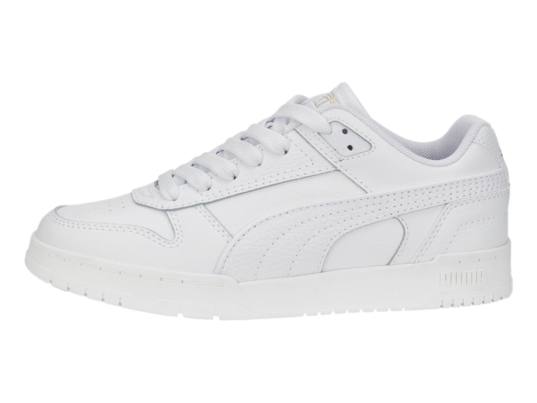 Tenis PUMA RBD Game Low JR en color blanco con detalles dorados, diseño deportivo de corte bajo para niños.