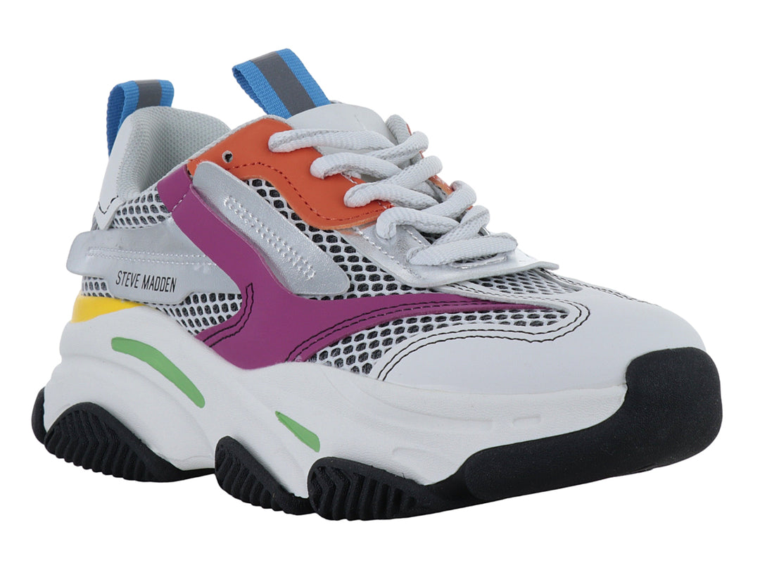 Tenis deportivos infantiles blancos con detalles multicolores y suela robusta negra.