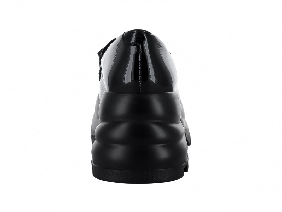 Zapato mocasín negro de piel brillante con plataforma gruesa y hebilla decorativa.