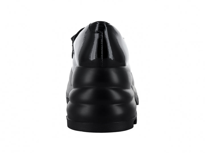Zapato mocasín negro de piel brillante con plataforma gruesa y hebilla decorativa.