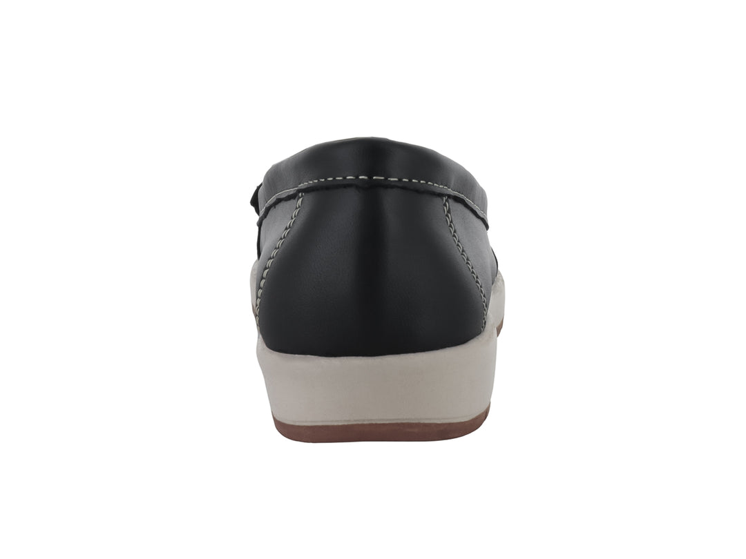Zapato tipo mocasín color negro con borlas decorativas y suela beige contrastante.