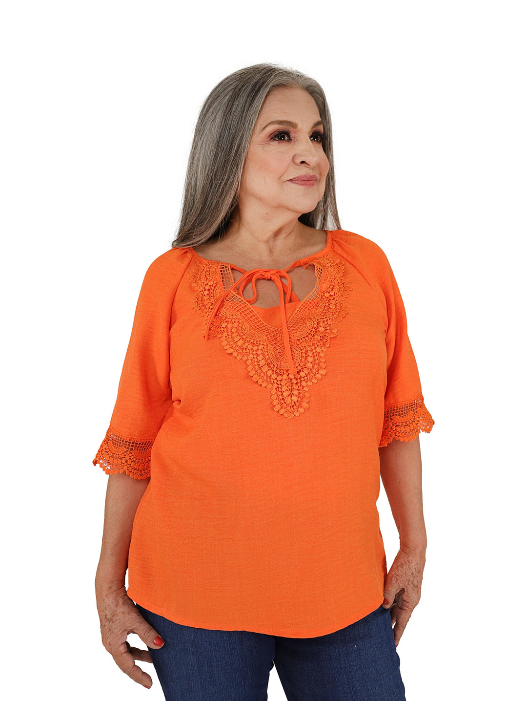 Mujer vistiendo blusa color naranja con detalles de encaje en el pecho y mangas.