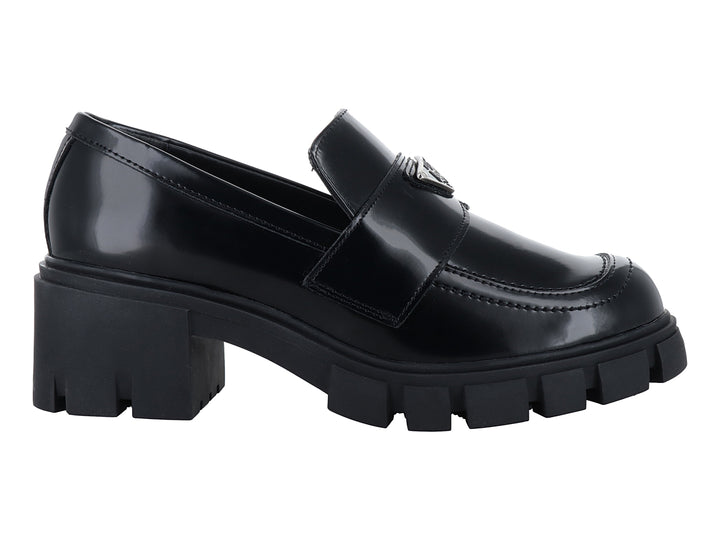 Mocasín negro brillante para mujer con suela de plataforma gruesa y detalle metálico.
