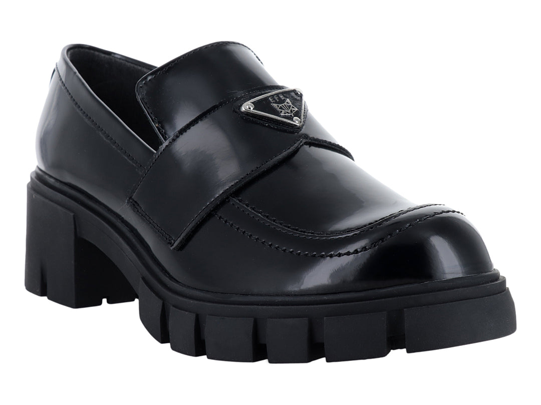 Mocasín negro brillante para mujer con suela de plataforma gruesa y detalle metálico.