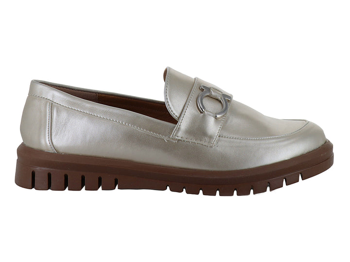 Zapato mocasín color plata metalizado con suela gruesa marrón y detalle decorativo frontal.