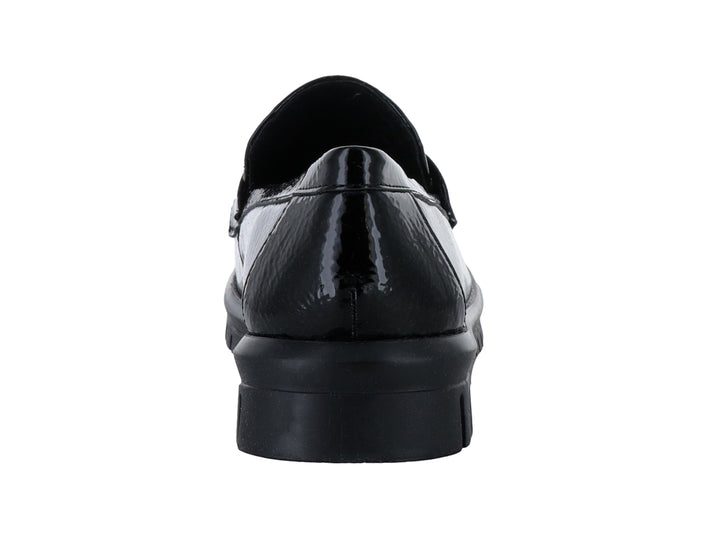 Zapato plano tipo mocasín Clinton en color negro de charol arrugado con hebilla plateada y suela gruesa.