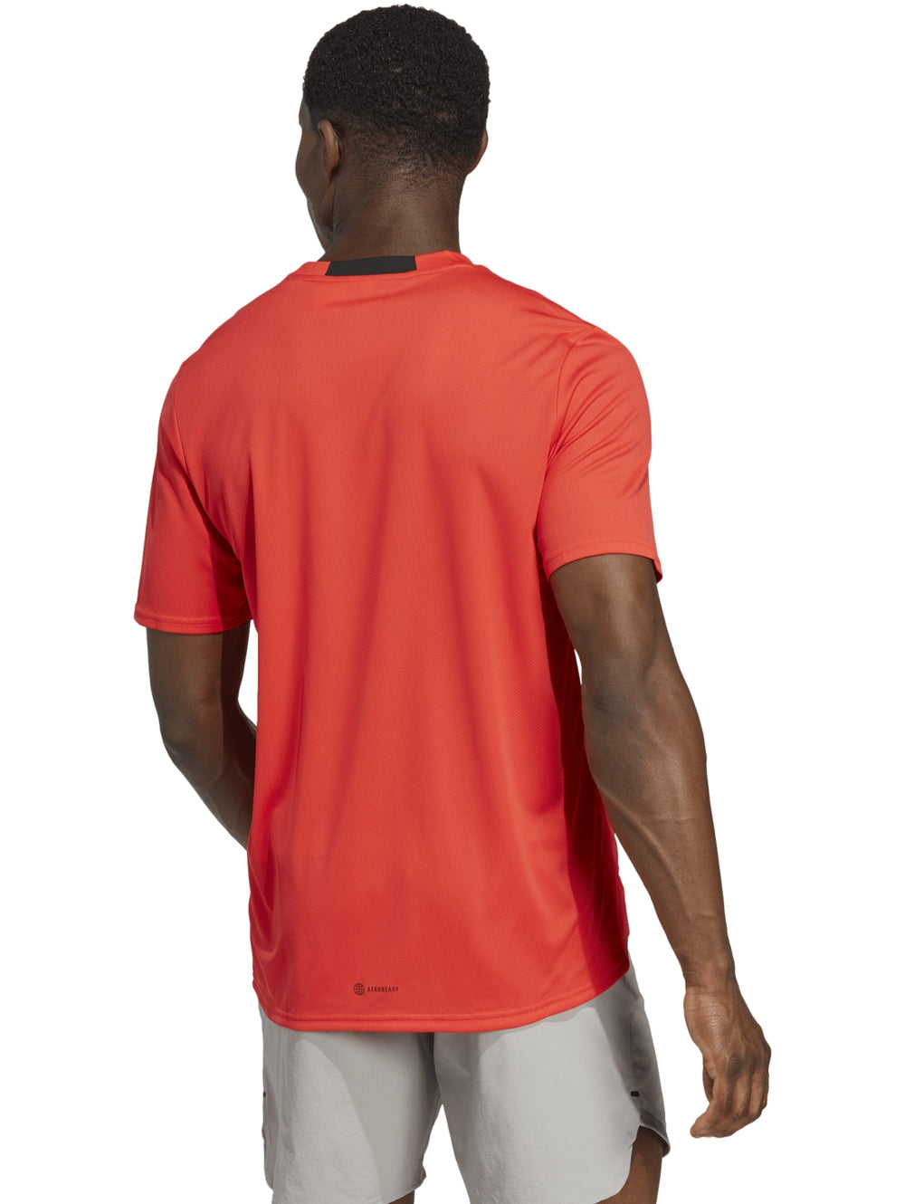 Camiseta deportiva Adidas de color rojo brillante con cuello redondo y manga corta.