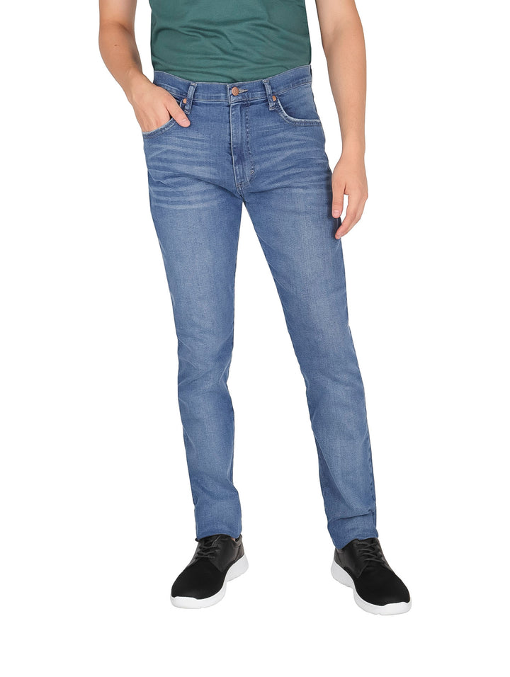 Hombre vistiendo pantalones jeans Wrangler azul claro de corte slim.