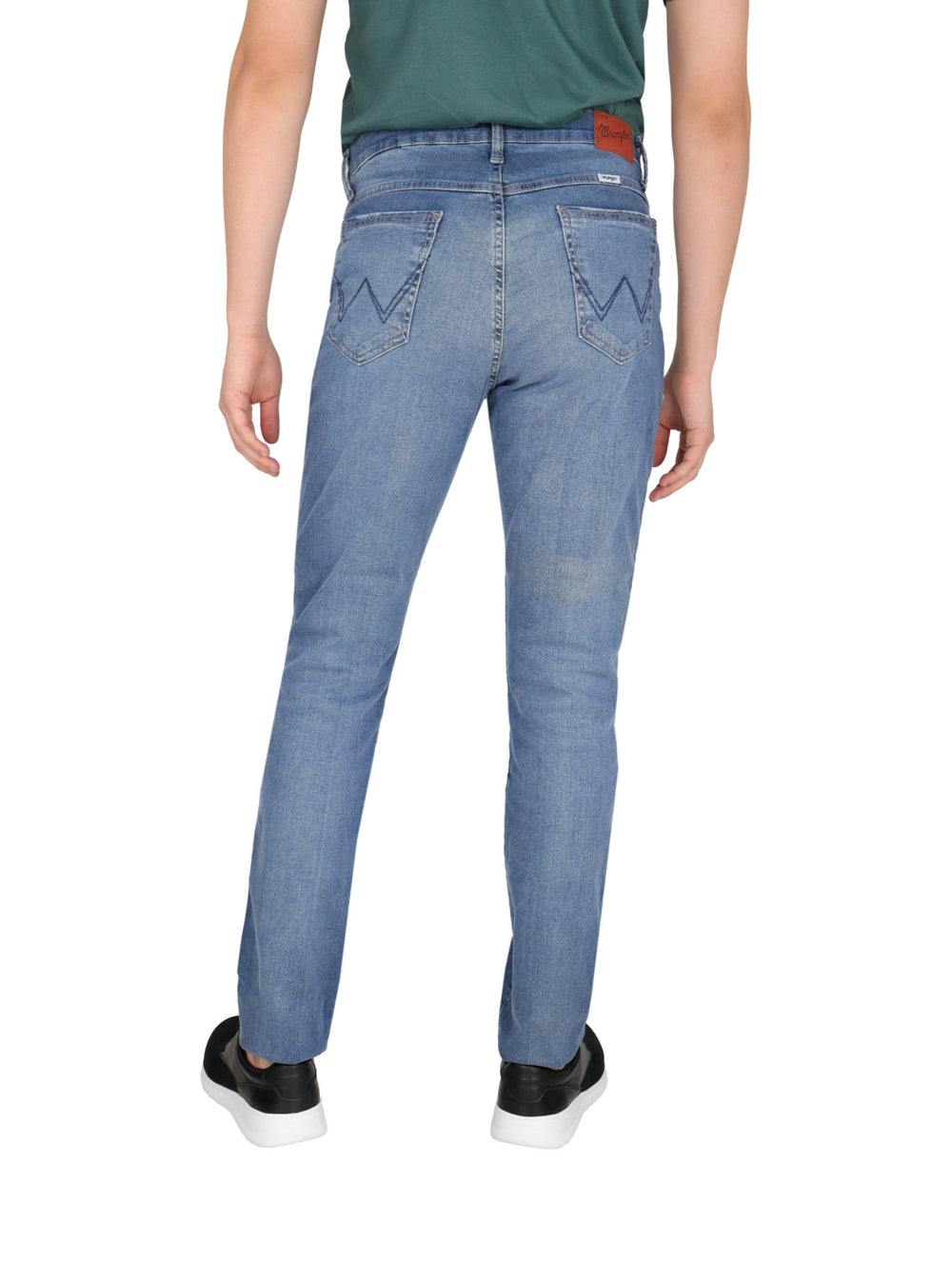 Hombre vistiendo pantalones jeans Wrangler azul claro de corte slim.