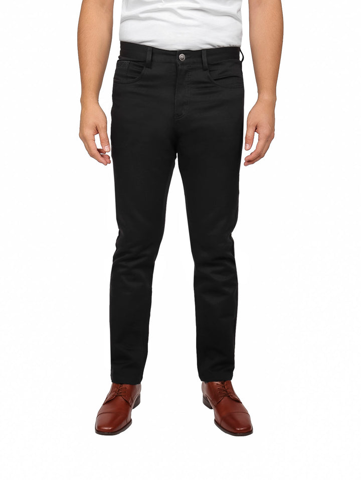 Hombre vistiendo un pantalón negro de corte ajustado con zapatos cafés y camiseta blanca.