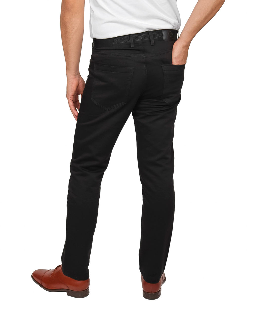 Hombre vistiendo un pantalón negro de corte ajustado con zapatos cafés y camiseta blanca.