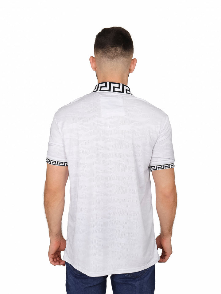Hombre vistiendo playera polo blanca con detalles decorativos negros en cuello y mangas.