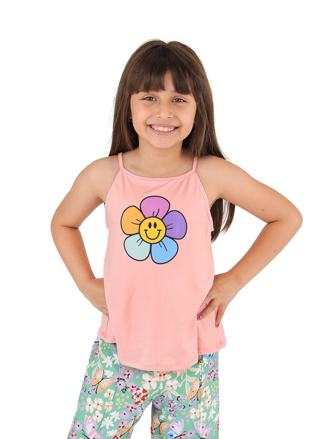Niña vistiendo un top deportivo color coral con estampado de flor sonriente y pantalones floreados.