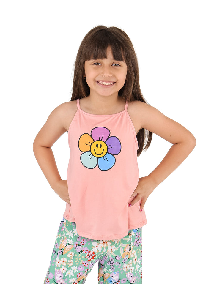 Niña vistiendo un top deportivo color coral con estampado de flor sonriente y pantalones floreados.