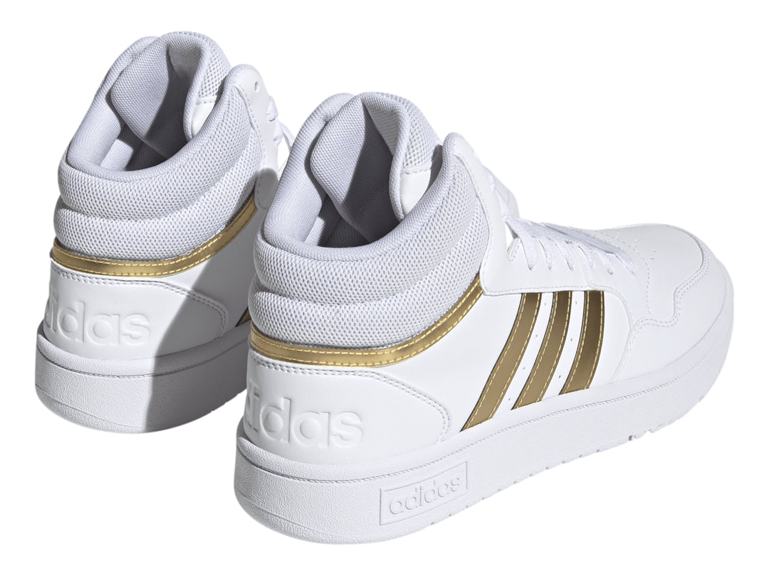 Tenis Adidas Hoops 3.0 Mid color blanco con franjas laterales doradas.