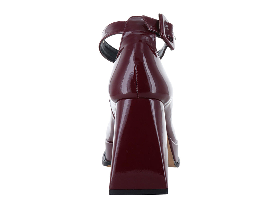 Zapato de tacón alto y plataforma color rojo cabernet con acabado brillante de charol y correa al tobillo.