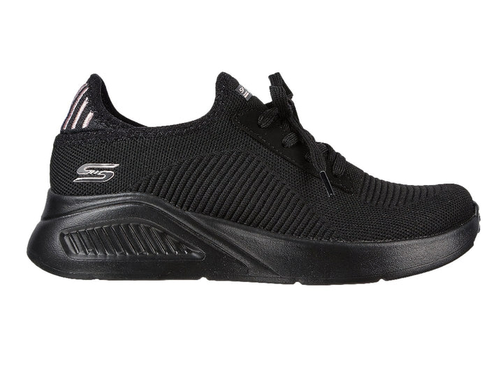 Tenis negros Skechers con tejido acanalado, detalles en rosa en el talón y suela gruesa.