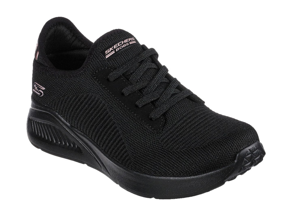 Tenis negros Skechers con tejido acanalado, detalles en rosa en el talón y suela gruesa.