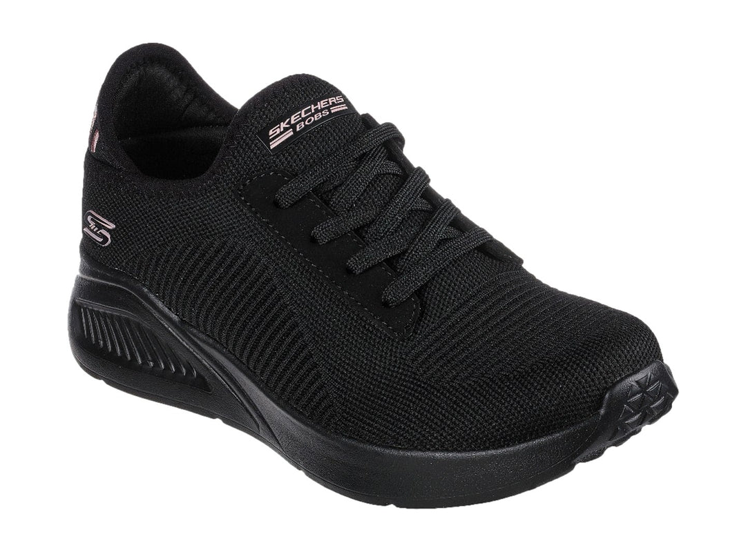 Tenis negros Skechers con tejido acanalado, detalles en rosa en el talón y suela gruesa.