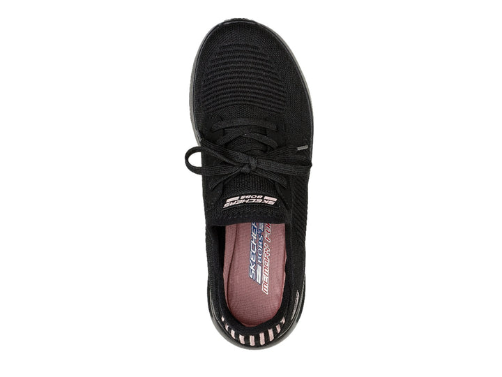 Tenis negros Skechers con tejido acanalado, detalles en rosa en el talón y suela gruesa.