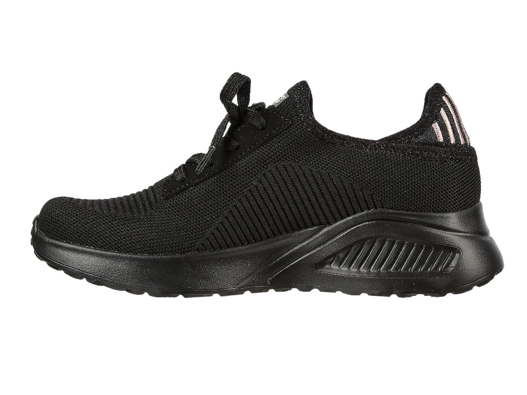 Tenis negros Skechers con tejido acanalado, detalles en rosa en el talón y suela gruesa.