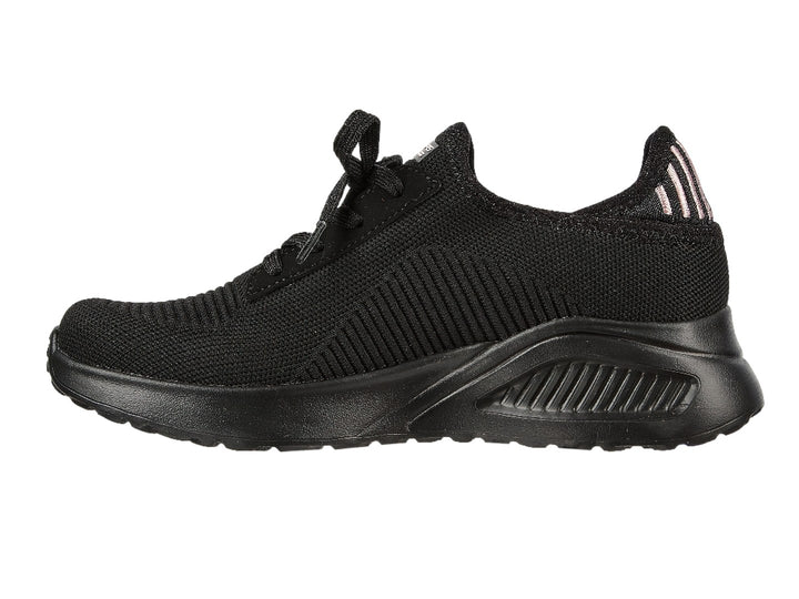 Tenis negros Skechers con tejido acanalado, detalles en rosa en el talón y suela gruesa.