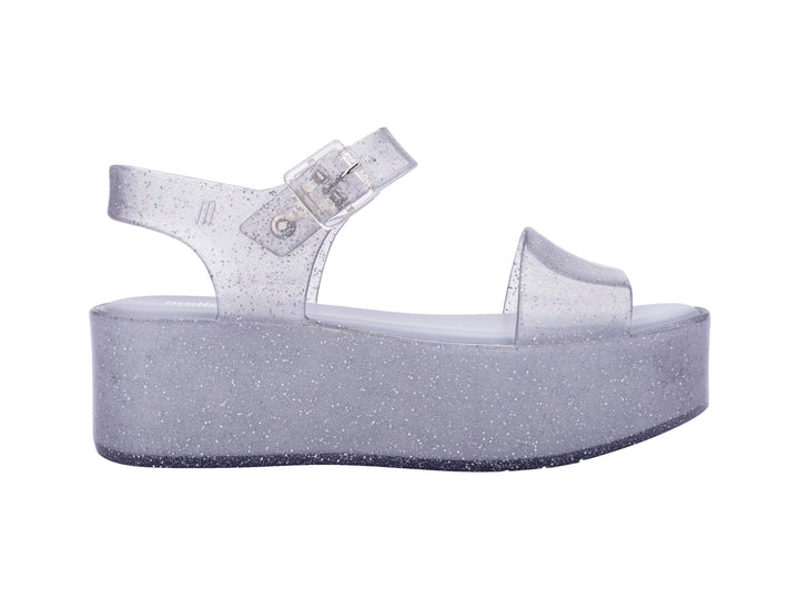 Sandalia de plataforma transparente con glitter y correa con hebilla.