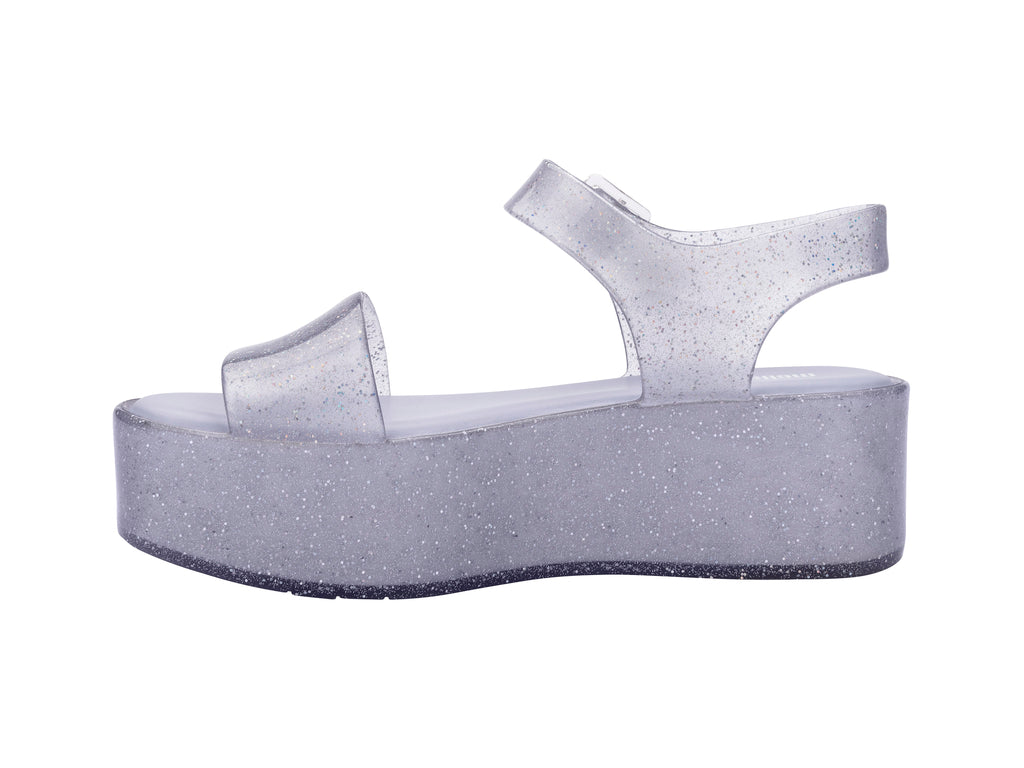 Sandalia de plataforma transparente con glitter y correa con hebilla.