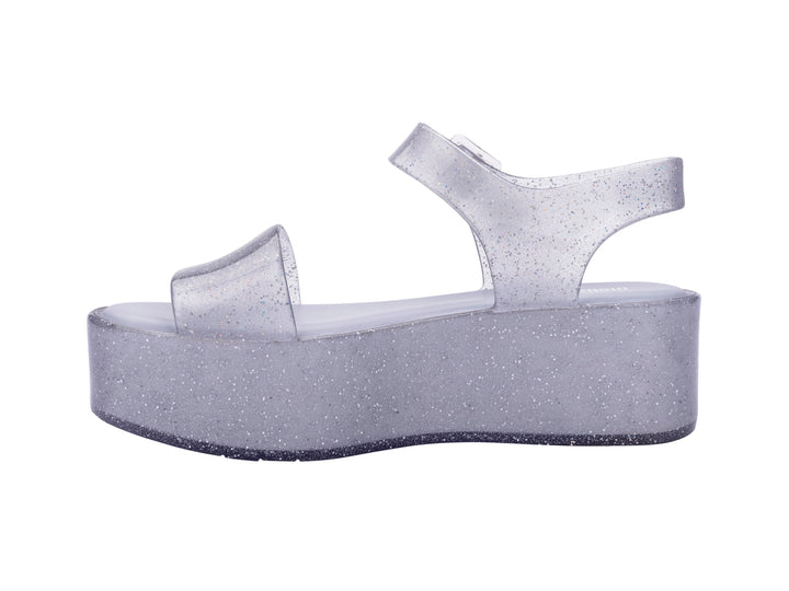 Sandalia de plataforma transparente con glitter y correa con hebilla.