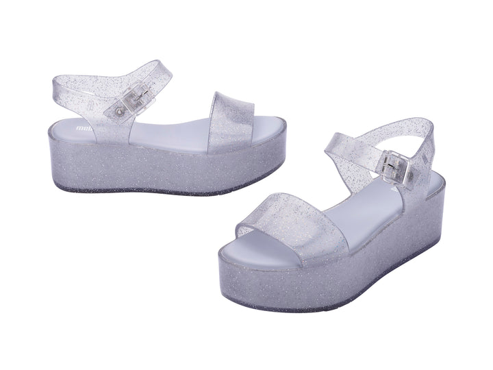 Sandalia de plataforma transparente con glitter y correa con hebilla.