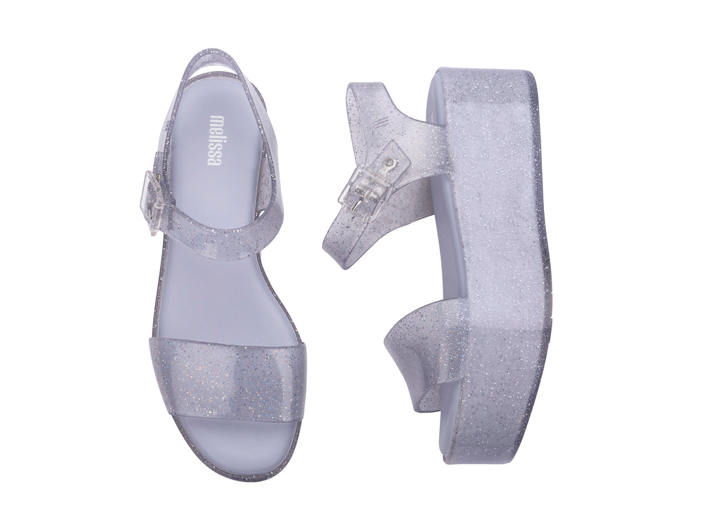 Sandalia de plataforma transparente con glitter y correa con hebilla.