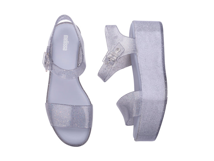 Sandalia de plataforma transparente con glitter y correa con hebilla.