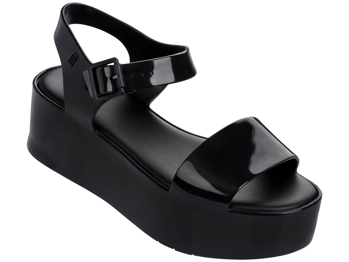 Sandalia Melissa de plataforma alta en color negro brillante con correa ajustable al tobillo.