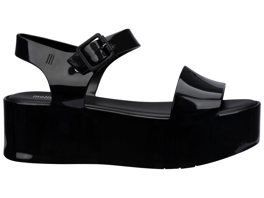 Sandalia Melissa de plataforma alta en color negro brillante con correa ajustable al tobillo.